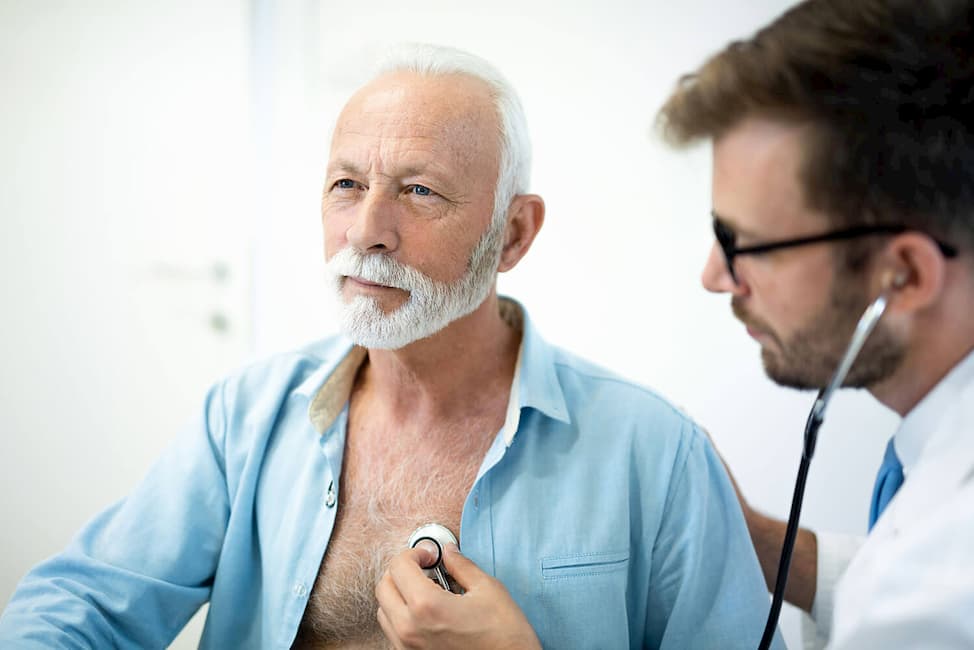 elderly man getting checked by a doctor using a stethoscope